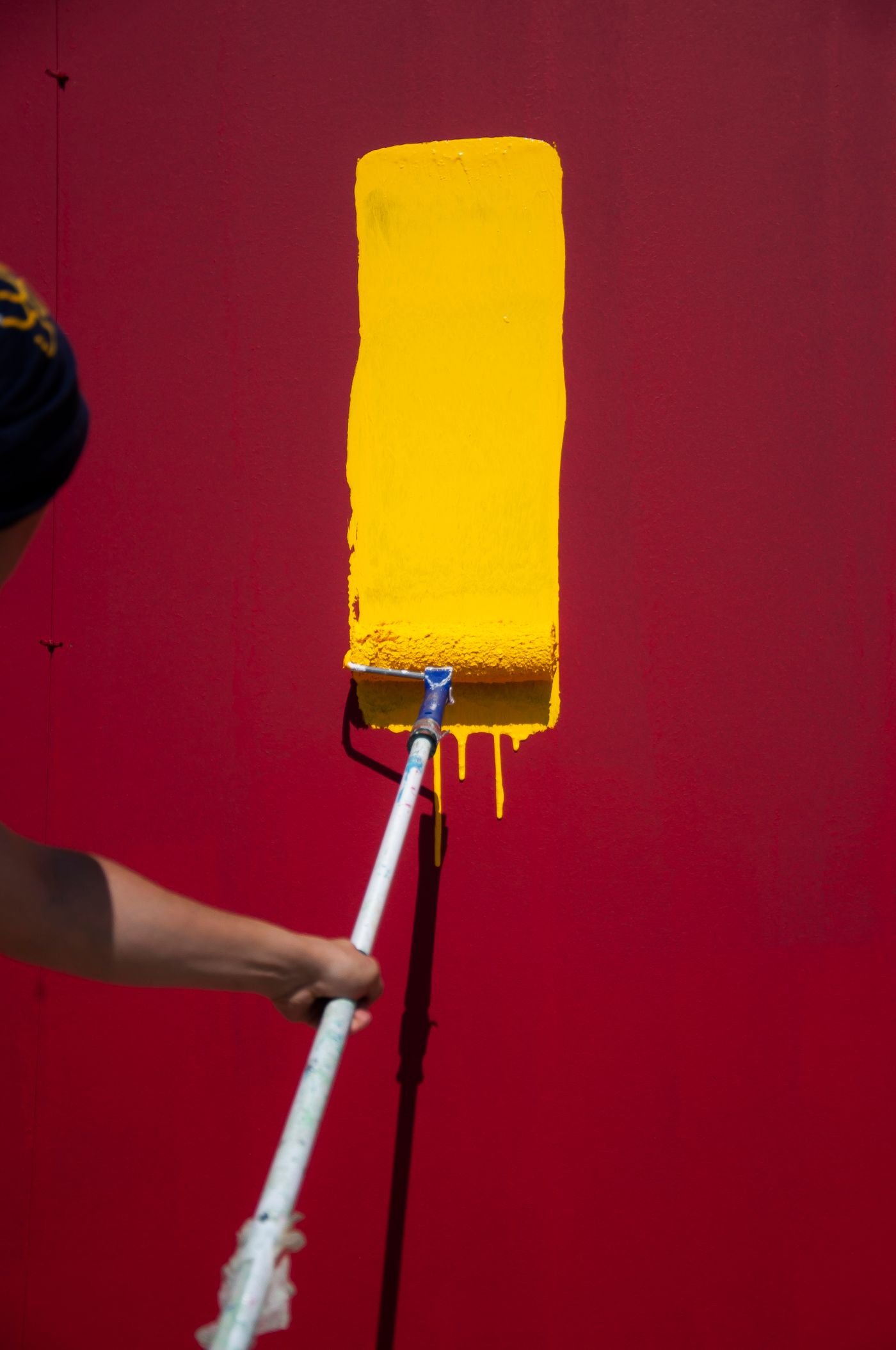 Paint roller applying bold colour on a wall - professional painting services in Dubai